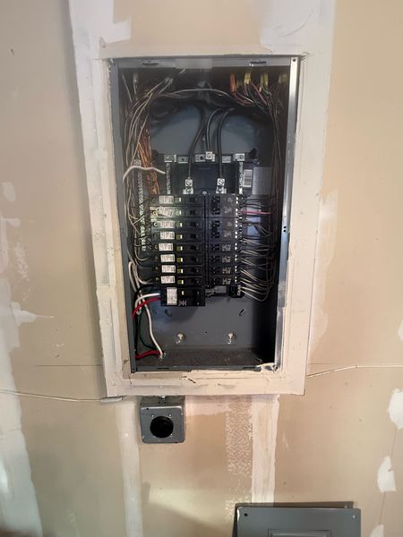 New breaker panel with the cover off, with an outlet installed below – Zion Electric Inc., San Leandro electrician