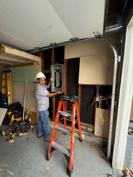 Zion Electric technician in a hard hat at a new panel in a garage – Zion Electric Inc., San Leandro electrician