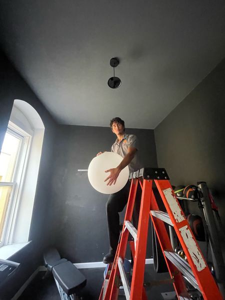 Zion Electric technician installing a globe pendant light in a home gym – Zion Electric Inc., San Leandro electrician