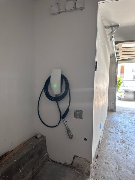 Tesla Wall Connector mounted in a garage, next to an outlet – Zion Electric Inc., San Leandro electrician